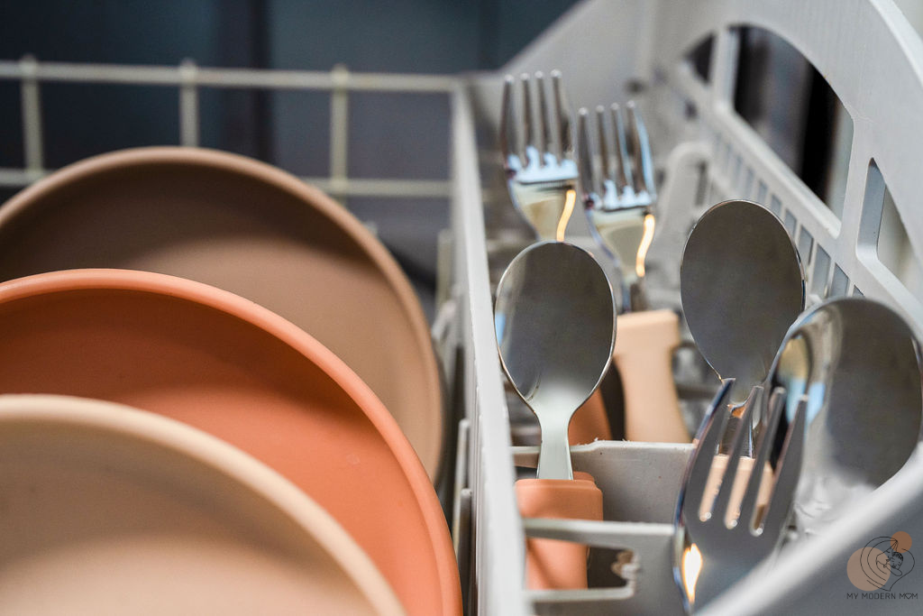 Dishwasher rack with plates, spoons, and forks.