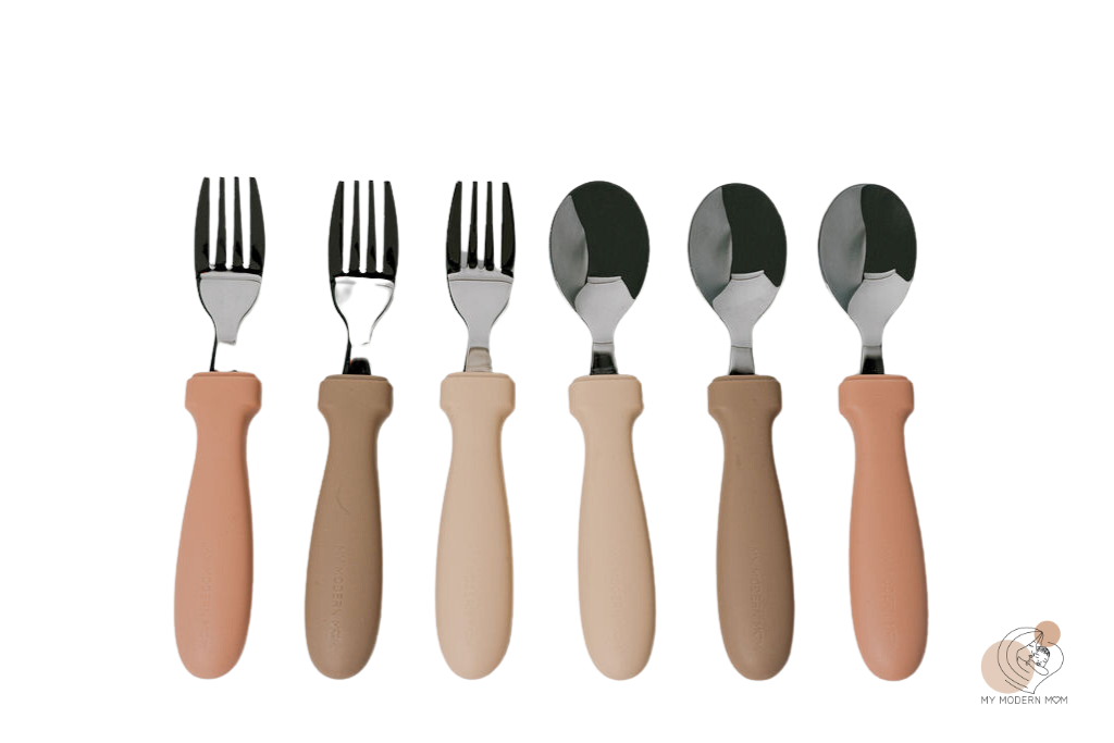A set of children's cutlery with ergonomic handles in various skin tones, including spoons and forks.