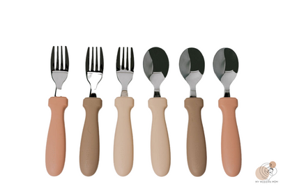 A set of children's cutlery with ergonomic handles in various skin tones, including spoons and forks.